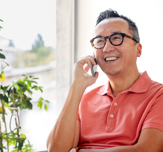 a man in pink polo shirt and glasses speaking on mobile phone
